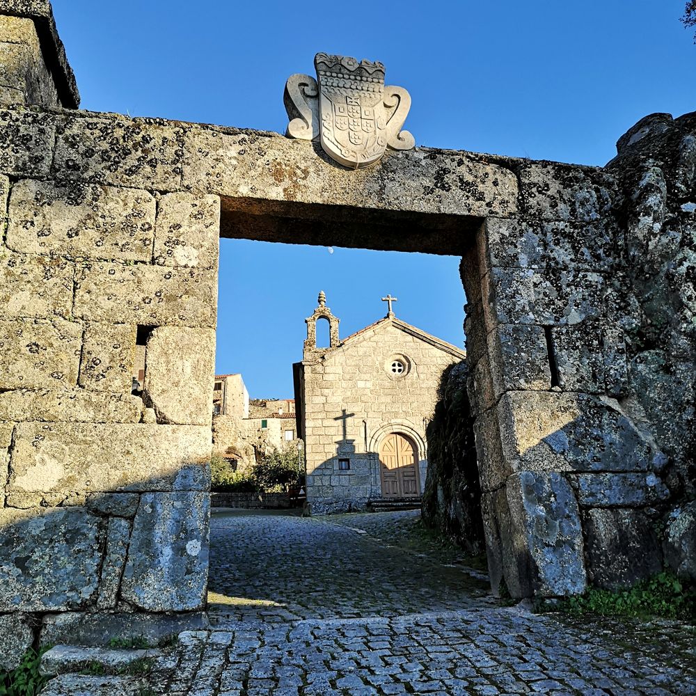Puerta de piedra con escudo que enmarca una capilla