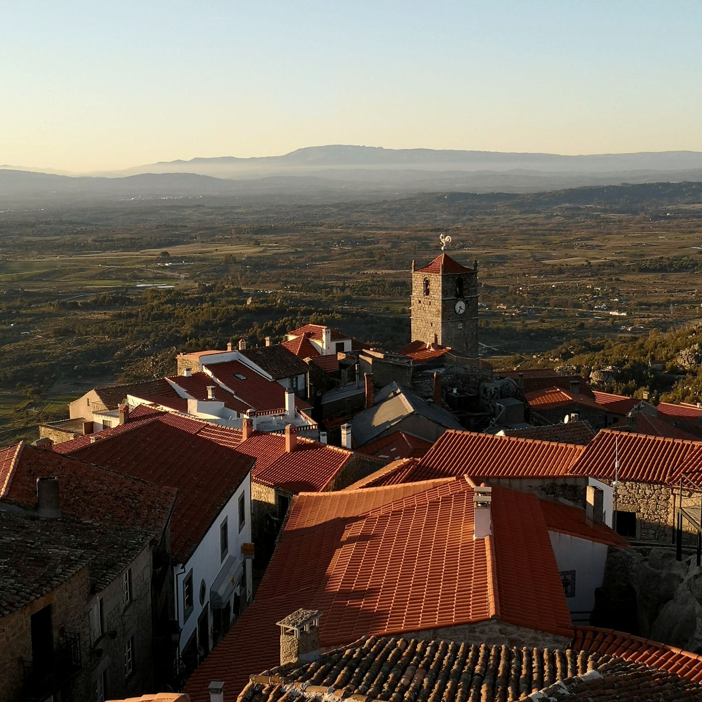 Tejados rojos y torre del reloj de Monsanto con la llanura al fondo