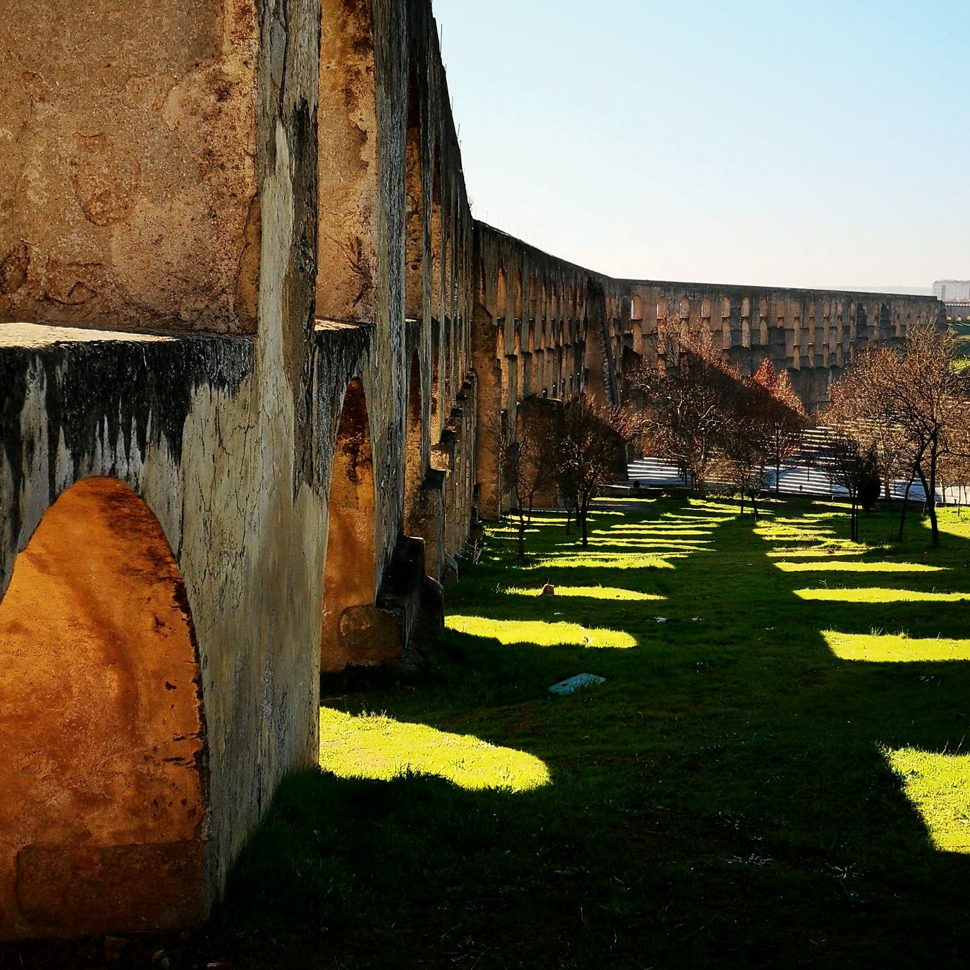 Arcos del acueducto de Amoreira proyectando sombras sobre la hierba