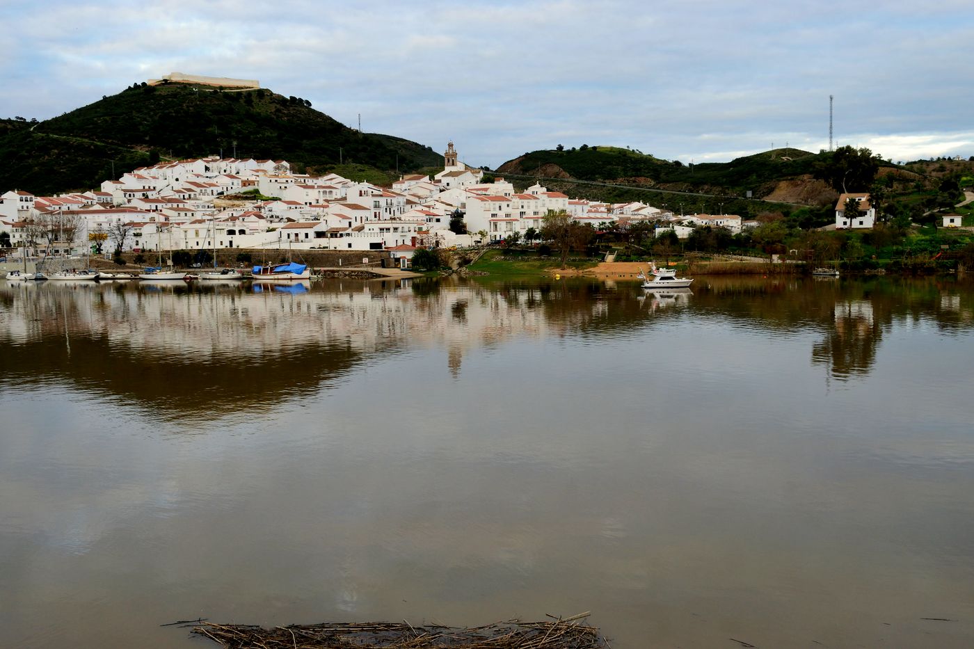 Sanlúcar de Guadiana, pueblo blanco junto al río con barcos amarrados y el castillo en lo alto